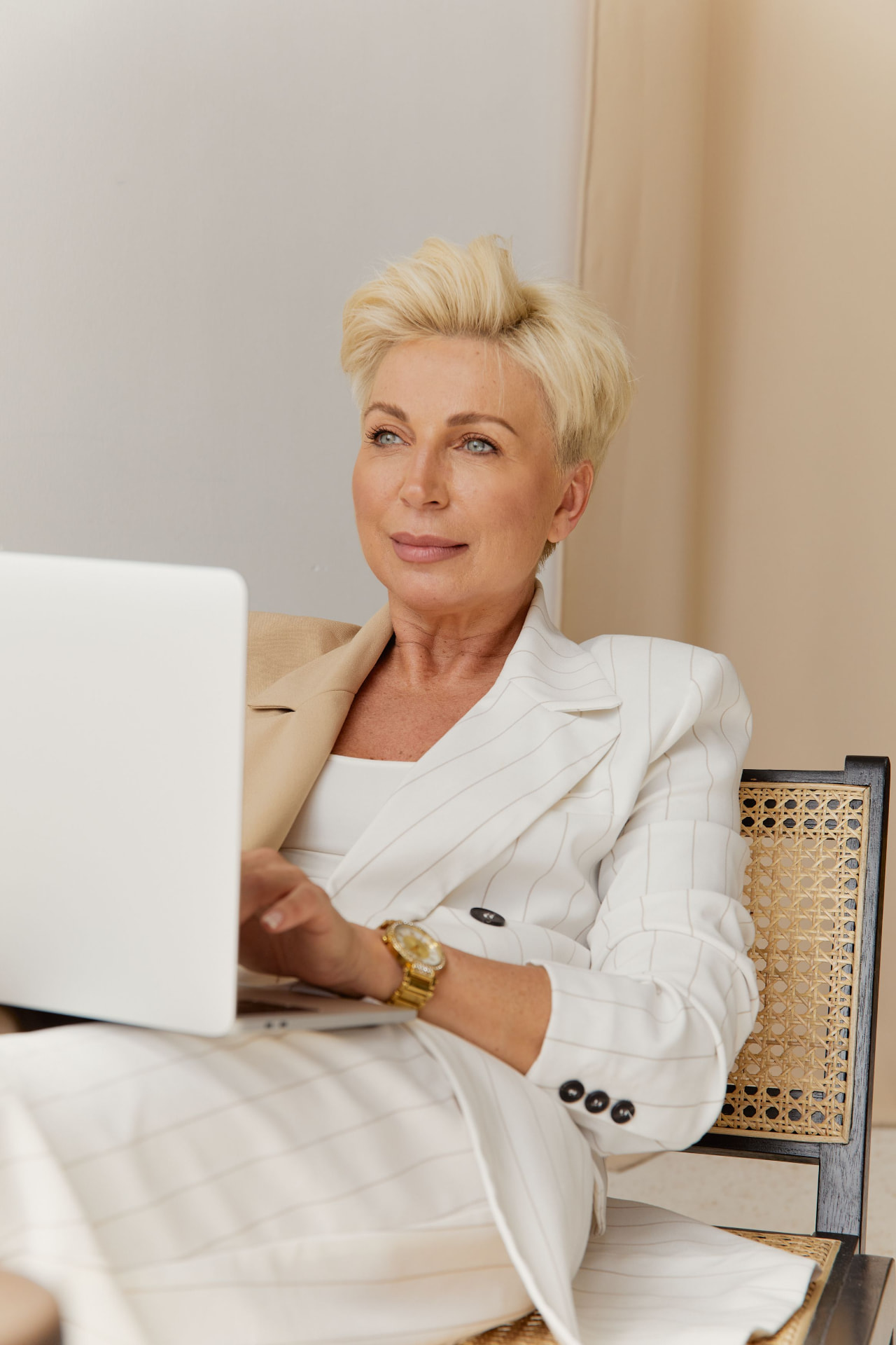Woman in a white suit working with a laptop