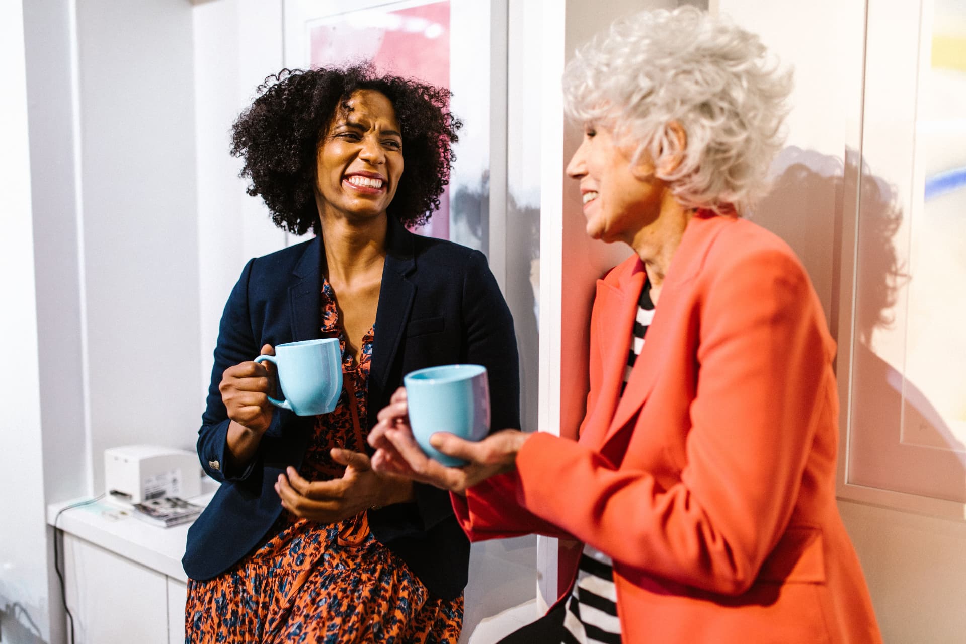 Two women chatting over coffee by a window